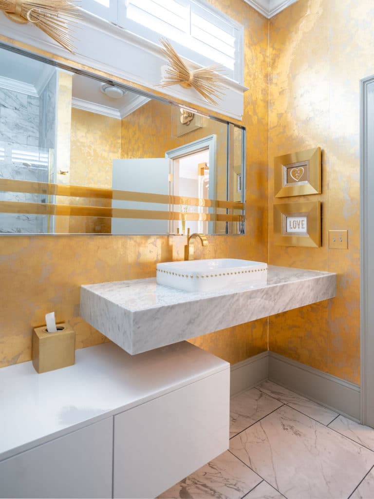 bathroom decor and design with a floating marble sink and gold walls.