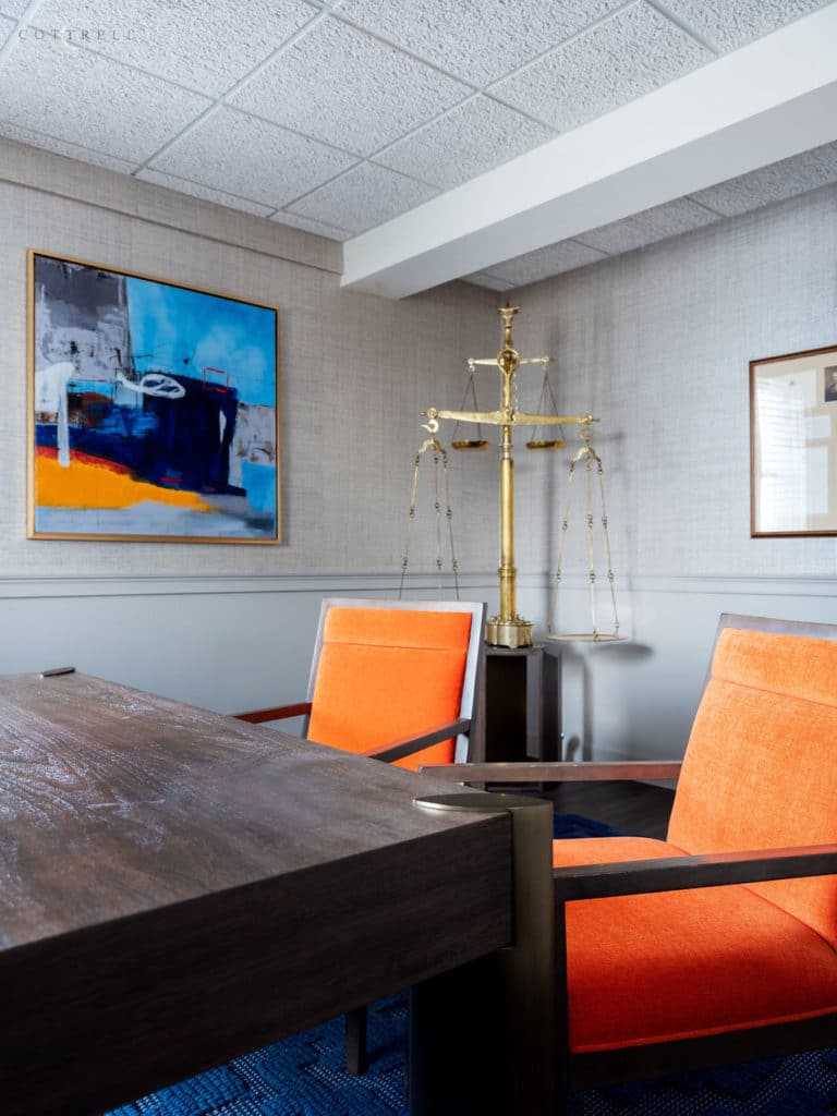 Home office with orange chairs and abstract sculpture.
